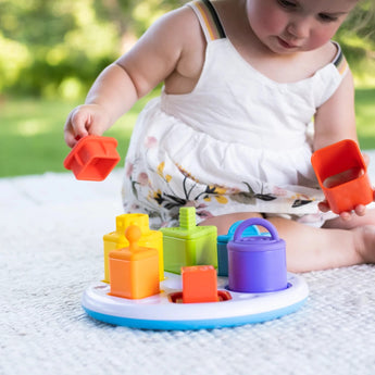 Toddler using Fat Brain Toy Cos Plugzy Shape Learning Toy outdoors for sensory learning and fine motor skill enhancement.