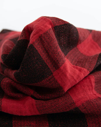 Close-up of a crumpled Cotton Swaddle, Red Plaid by Little Unicorn on a plain background.