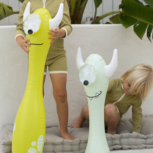 Two kids in matching outfits play indoors with Sunnylifes Monty the Monster inflatable pool noodles, sparking their imaginations.
