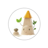A Creative Sand Play scene by PlanToys features a smiling sandcastle with a yellow cone roof and leafy branches beside a stone-topped mound.