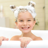 A smiling child enjoys bubbles with foam animal ears in a Piggy Paint 3-in-1 Shampoo + Body Wash + Bubble Bath.