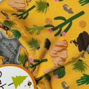 Close-up of Arizona Animals fabric by Cabooties: yellow background with green trees and brown logs, like baby shoes with elastic ankles.