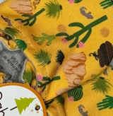 Close-up of Arizona Animals fabric by Cabooties: yellow background with green trees and brown logs, like baby shoes with elastic ankles.