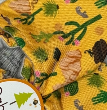 Close-up of Arizona Animals fabric by Cabooties: yellow background with green trees and brown logs, like baby shoes with elastic ankles.