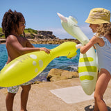 Kids play joyfully by the sea with Sunnylifes Monty the Monster green inflatable noodles, embracing fun water play.