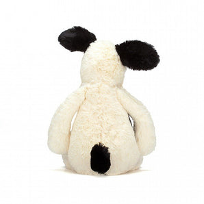 Bashful Black & Cream Puppy by Jellycat, featuring white fur and black ears, shown from the back.