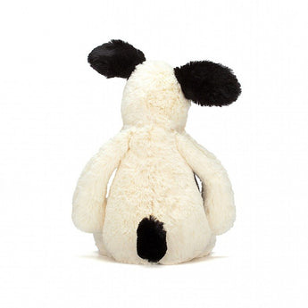 Bashful Black & Cream Puppy by Jellycat, featuring white fur and black ears, shown from the back.