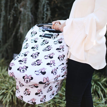 Someone in a white blouse pushes a stroller with a Milk Snob Cover featuring Disneys Minnie Mouse patterns.