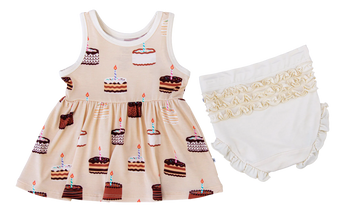 The Blake Birdie Peplum Set by Birdie Bean features a sleeveless cake print dress and ivory ruffled bloomers for a charming look.