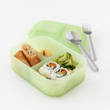 Bumkins Silicone Bento Box 3 Section: Green Jelly holds sushi rolls, salad, and a spring roll. Utensils rest on the lid on a white background.