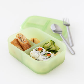 Bumkins Silicone Bento Box 3 Section: Green Jelly holds sushi rolls, salad, and a spring roll. Utensils rest on the lid on a white background.