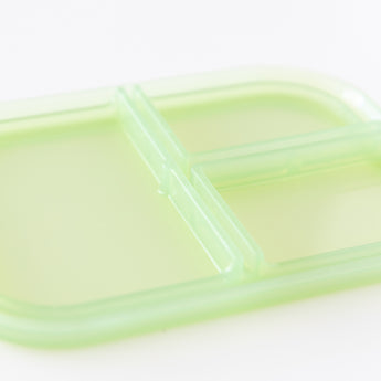 Close-up of the lid of Bumkins Silicone Bento Box 3 Section: Green Jelly, made of LFGB-grade silicone, on a white background.