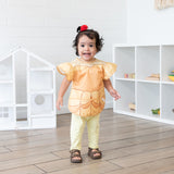 A girl in a ponytail smiles in a bright playroom, wearing a bib from Bumkins Snack In Character 4-Piece Set: Disney Princess Magic Belle.