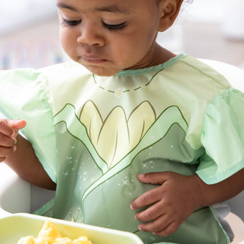 Close-up of a girl wearing a bib from Bumkins Snack In Character 4-Piece Set: Disney Princess Magic Tiana.