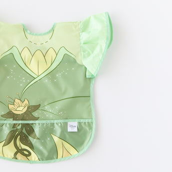 Bumkins Ruffle Apron Bib: Tiana is shown on a white background, partially out of frame.