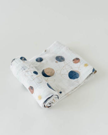 The Little Unicorn Cotton Swaddle, Planetary features hand-painted space-themed prints of planets and stars on light gray cotton muslin.