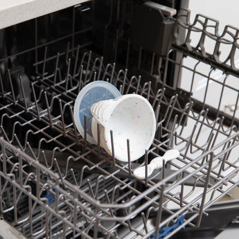 Bumkins Silicone First Feeding Set: Vanilla Sprinkle sits in the top rack of an open dishwasher.