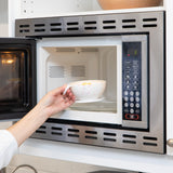 A person places a Bumkins Silicone First Feeding Set: Vanilla Sprinkle filled with food into an open microwave.