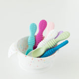 Bumkins Silicone First Feeding Set: Vanilla Sprinkle with colorful baby spoons inside on a white background.