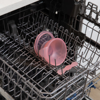 Bumkins Silicone First Feeding Set: Pink Jelly sits in the top rack of an open dishwasher.