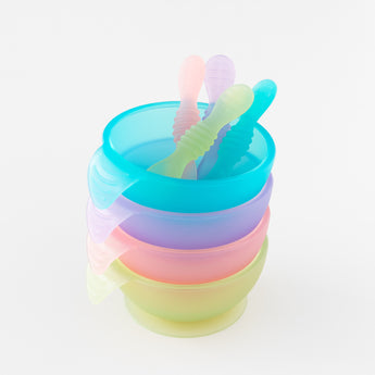 A stack of four colorful bowls with spoons, on a white background, including Bumkins Silicone First Feeding Set: Pink Jelly.