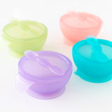 Bumkins Silicone First Feeding Set: Purple Jelly sits among other colorful bowl and spoon sets on a white background.