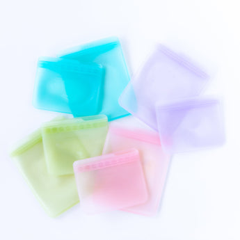 Bumkins Silicone Flat Reusable Bag 2 Pack, Blue lays among other similar bags sets on a white background.