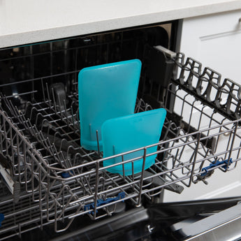 Bumkins Silicone Flat Reusable Bag 2 Pack, Blue sits in the top rack of an open dishwasher.