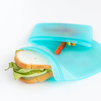 A sandwich with lettuce, and sliced bell peppers in Bumkins Silicone Flat Reusable Bag 2 Pack, Blue on a white background.