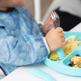 Close-up of a child enjoying self-feeding with Bumkins On-The-Go Mealtime 6-Piece Set: Denim + Blue.