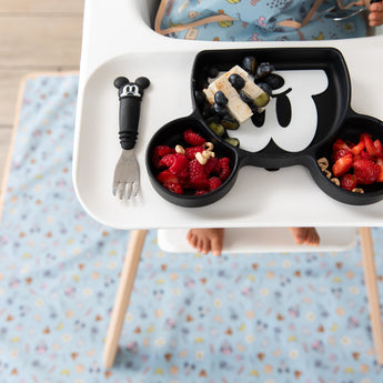 Bumkins Grip Dish Essential 3-Piece Mealtime Set: Disney Mickey Mouse with fruit sits on a high chair tray above a blue waterproof mat.