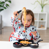 A child eats spaghetti and fruit with Bumkins Grip Dish Essential 3-Piece Mealtime Set: Disney Mickey Mouse in a cozy living room.