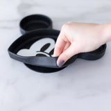 A hand holds a dish from Bumkins Grip Dish Essential 3-Piece Mealtime Set: Disney Mickey Mouse, demonstrating the suction cup bottom.