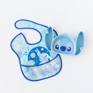Bumkins Silicone Grip Dish: Stitch lays beside a blue Stitch space-themed bib on a white background.