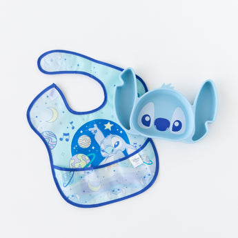 Bumkins Silicone Grip Dish: Stitch lays beside a blue Stitch space-themed bib on a white background.
