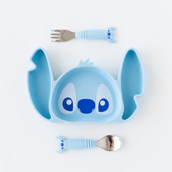 Bumkins Spoon + Fork: Stitch sits by a Stitch-shaped silicone plate on a white background.