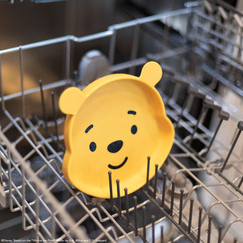 A dish from Bumkins Grip Dish Essential Infant 3-Piece Mealtime Set: Disney Winnie the Pooh sits in the top rack of an open dishwasher.