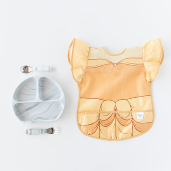 Bumkins Ruffle Apron Bib: Belle rests next to a gray marbled divided plate and matching utensils on a white background.