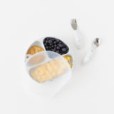Bumkins Spoon + Fork: Marble rests next to a divided plate with fruit & eggs with a transparent lid on a white background.