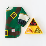 Bumkins Sleeved Bib: Zelda™ lays folded next to a yellow triangle plate with fruit and avocado on a white background.