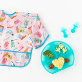 Bumkins Silicone Grip Dish: Blue Jelly with veggies lays on a white background with matching utensils and a pink cowboy boot patterned bib.