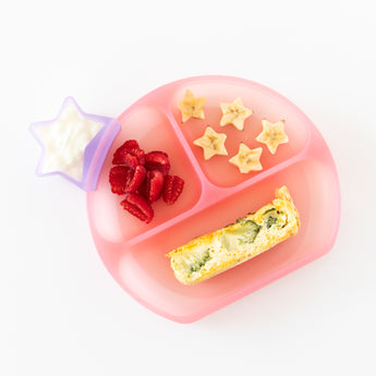 Bumkins Silicone Grip Dish: Pink Jelly filled with banana stars, strawberries, and quiche, with a star cup of yogurt on a white background.