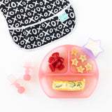 Bumkins Silicone Grip Dish: Pink Jelly with quiche and fruit sits next to a bib, utensils, and a star cup of yogurt on a white background.