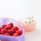 Close-up of Bumkins Silicone Grip Dish: Purple Jelly with raspberries and a pink heart-shaped cup of whipped cream on a white background.