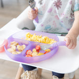 A child enjoys eggs and fruit from a Bumkins Silicone Grip Dish: Purple Jelly using a purple fork while in a high chair.