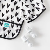 Close-up of Bumkins Silicone Chewtensils®: Marble next to a black & white heart-patterned sleeved bib on a white background.