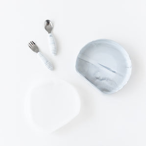 The Bumkins Grip Plate Essential 4-Piece Mealtime Set in Marble includes a bowl, spoon, fork, and lid on a white background.