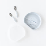The Bumkins Grip Plate Essential 4-Piece Mealtime Set in Marble includes a bowl, spoon, fork, and lid on a white background.