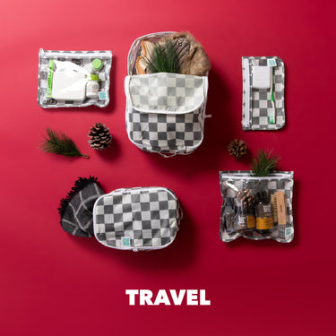Travel accessories and toiletries in checkered bags on a red background, with pine cones and greenery, text TRAVEL at the bottom.