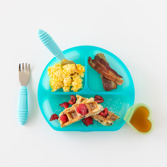 A blue divided plate with breakfast foods, utensils, and a Bumkins Silicone Little Dipper Combo 2 Pack: Aqua Jelly on a white background.